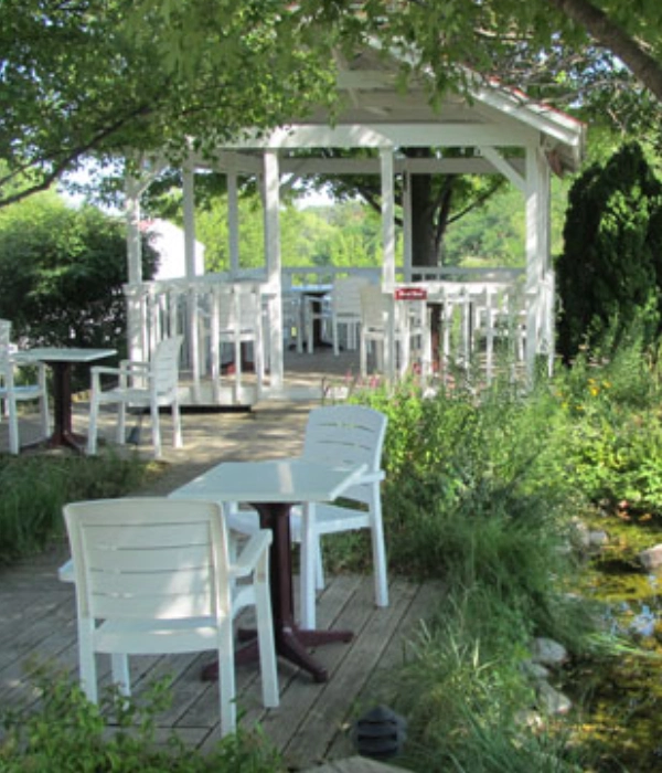 Cozy outdoor seating area with white chairs and tables in a garden setting.