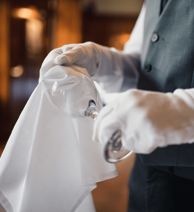Gloved hands polishing a wine glass