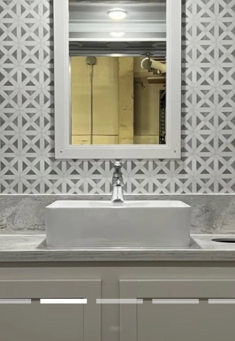 Modern bathroom sink with geometric patterned wall tiles.